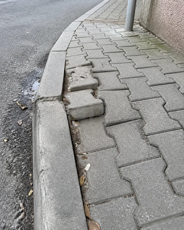 Kaldırım kenarında yükselmiş ve yerinden çıkmış kilit taşları